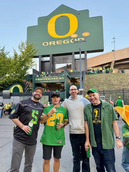 Three guests pose together outside Autzen Stadium.