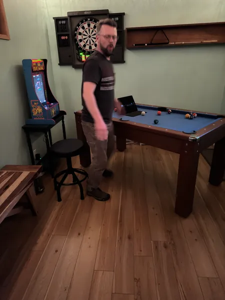 A guest stands beside a pool table.
