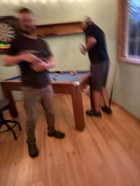 Two guests consult their phones near the pool table.