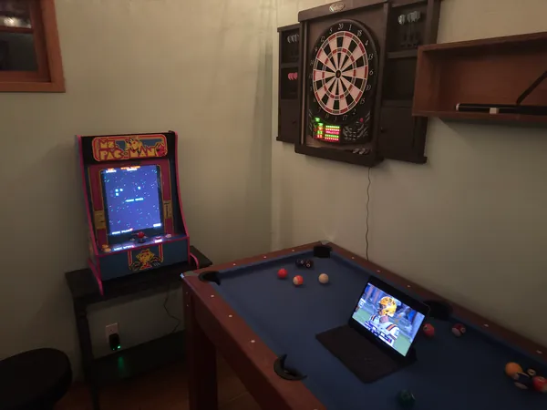 A pool table, electronic dartboard, and tablet scoreboard.