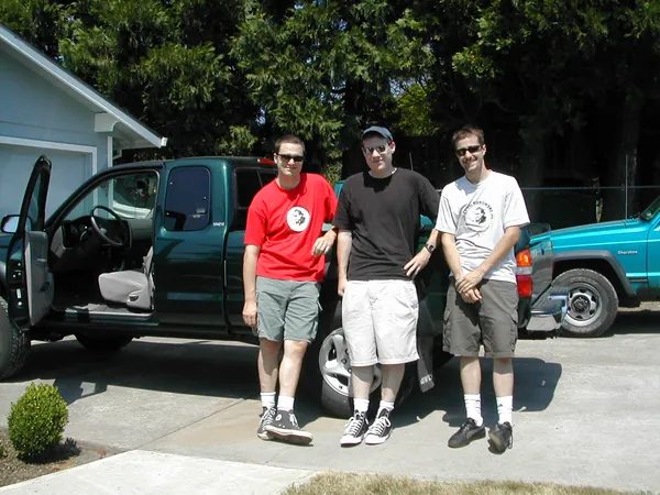 Three travelers gather between the packed vehicles.