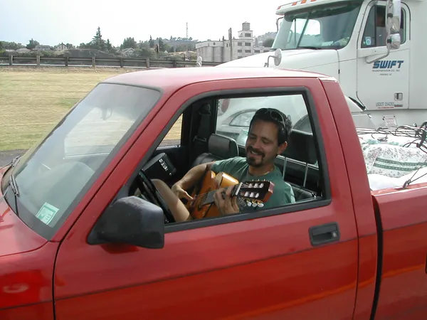 A smiling driver looks out from a red pickup.