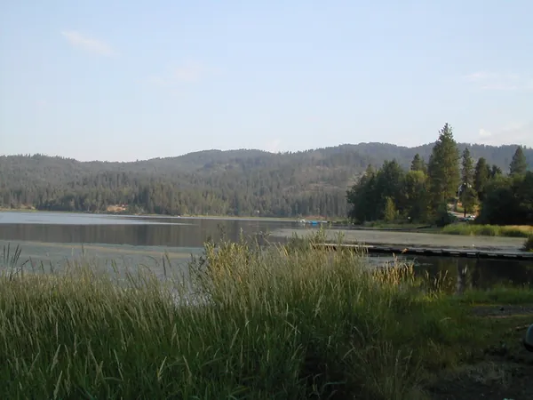 A calm mountain lake beneath wooded hills.