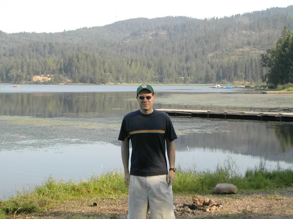A traveler stands at the edge of the mountain lake.