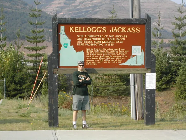 A traveler stands beneath a roadside historical marker.