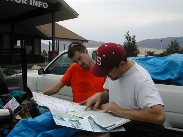 Two travelers consult road maps on the pickup tailgate.