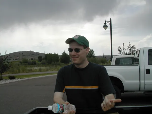 A traveler stands near the pickup beneath darkening clouds.