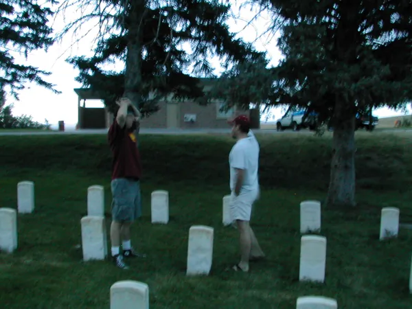 Travelers walk between cemetery markers at dusk.