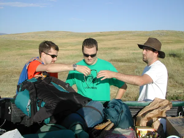 Travelers reorganize bags and gear at a roadside stop.