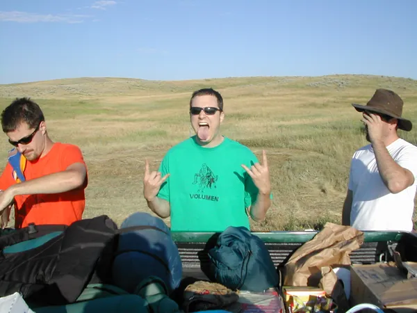 Three travelers sit among the luggage.