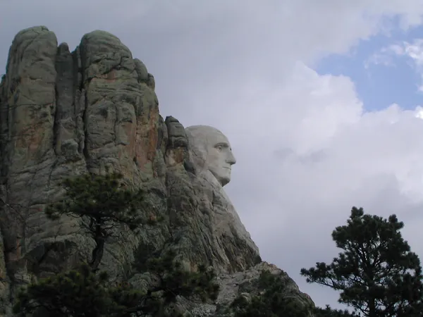 Mount Rushmore seen from below the surrounding pines.