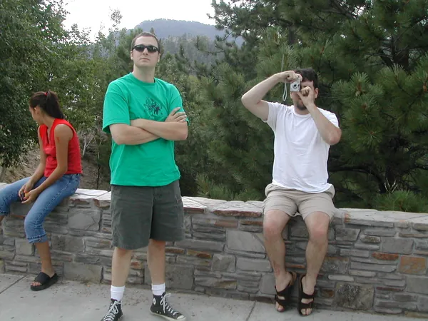 Two travelers sit on a stone wall at the overlook.