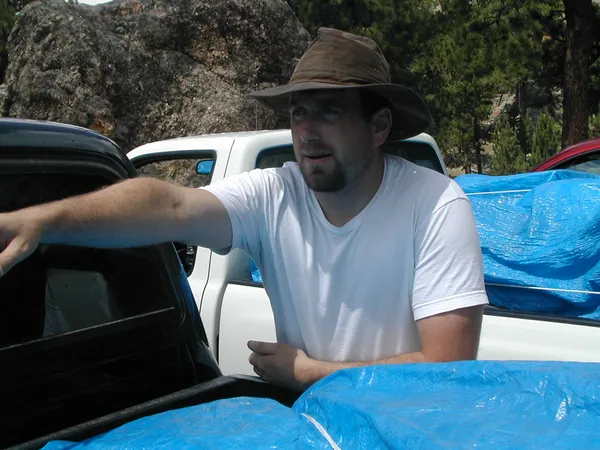 A traveler leans against the open pickup bed.