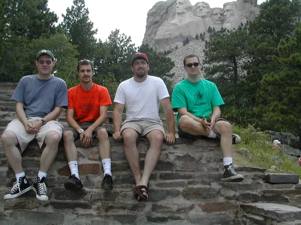Four travelers sit together on a stone wall.