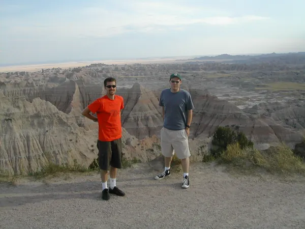 Two travelers stand farther back from the overlook.