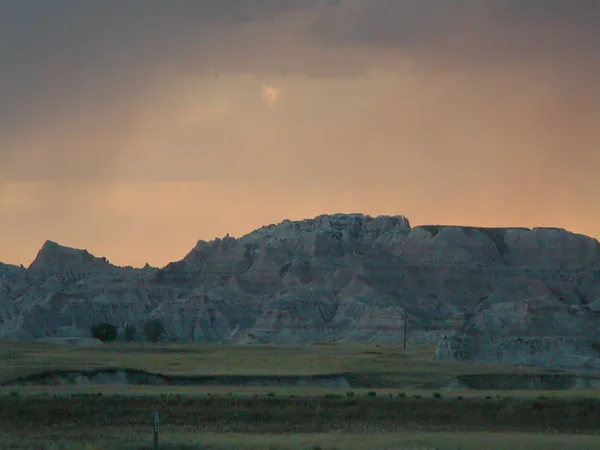 Orange sky above a dark rock formation.