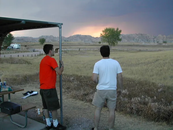 Two travelers stand beneath a sheltered overlook.