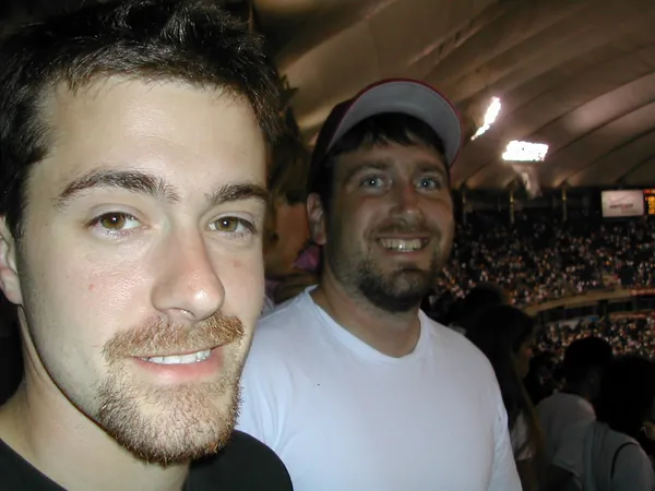 Two travelers take a photograph together in the stands.