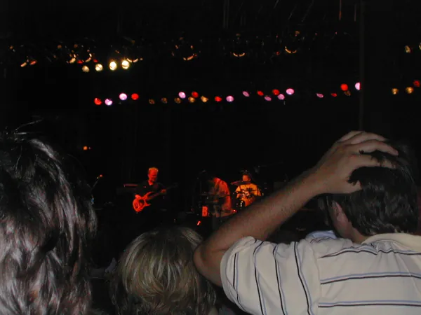 The crowd faces a brightly lit concert stage.