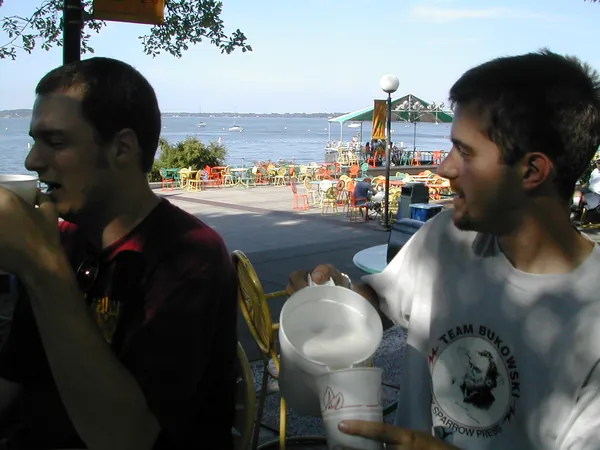 Two travelers stand near a waterfront attraction.