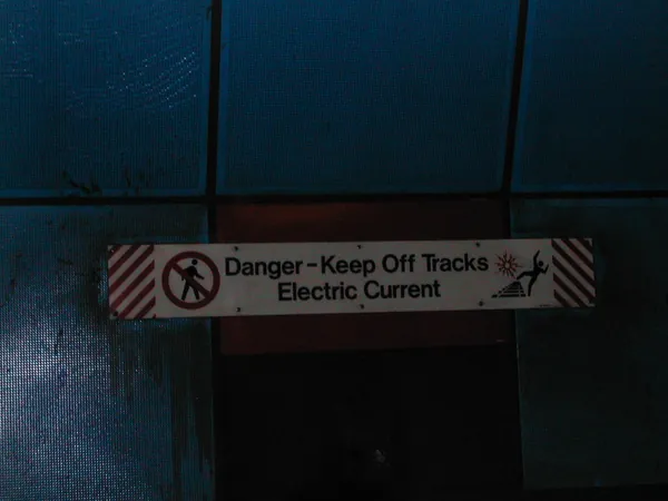 A transit warning sign above an escalator.