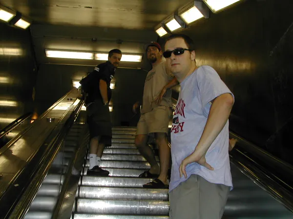 Travelers ride an escalator toward street level.