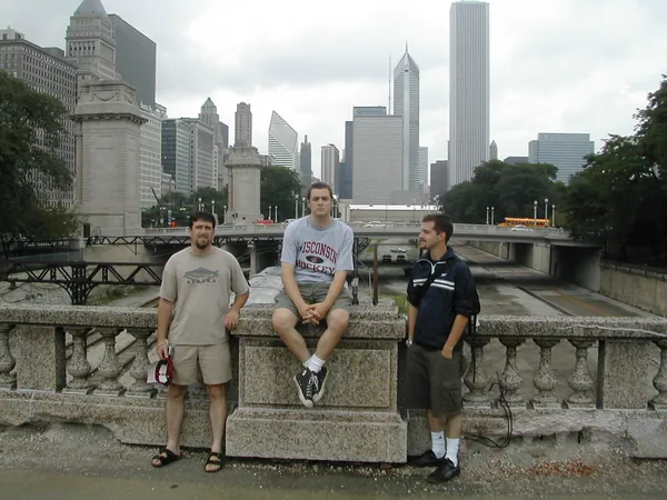 Three travelers sit on a stone railing.
