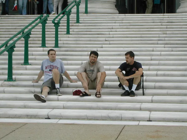 Three travelers sit together on broad stone steps.