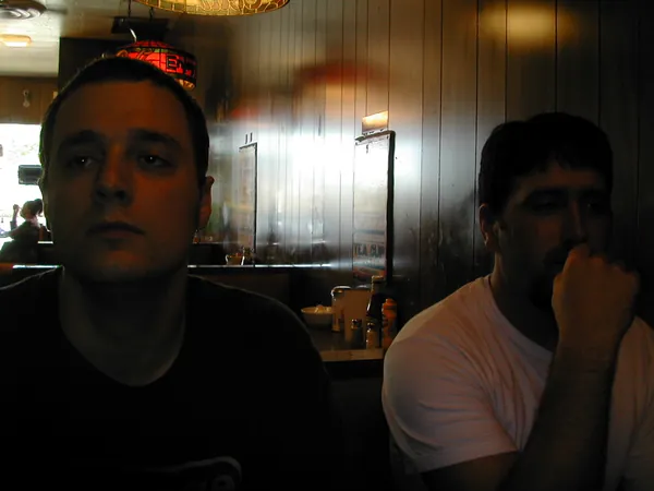 Two travelers sit in a dim restaurant.