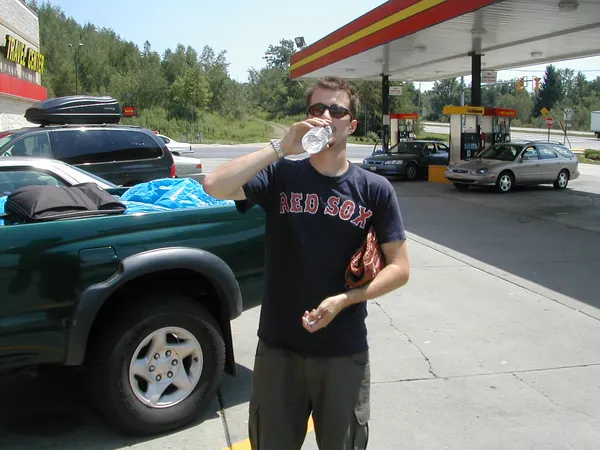 A traveler pauses beside the pickup at a gas station.