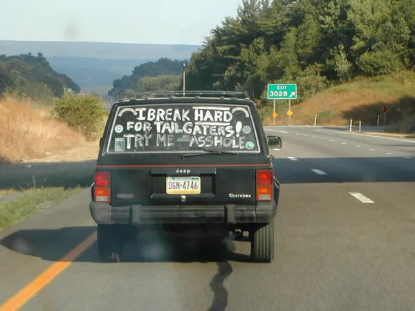 A van ahead bears a handwritten message across its rear.
