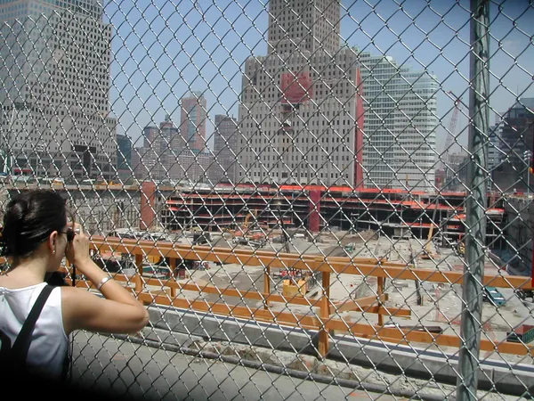 A visitor looks through a fence toward the site.
