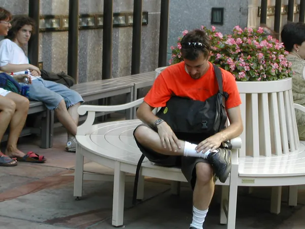 A traveler in a red shirt rests on a bench.