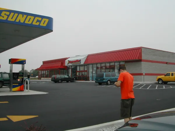 A traveler walks across the gas-station lot.