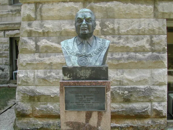 A bronze bust mounted against a stone wall.