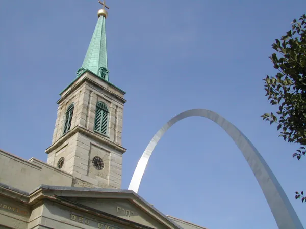 A church tower framed beside the Gateway Arch.