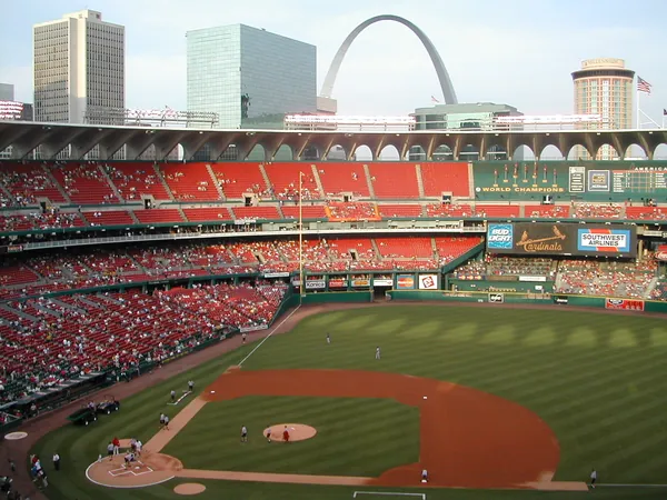 A baseball game underway in a red-seated stadium.