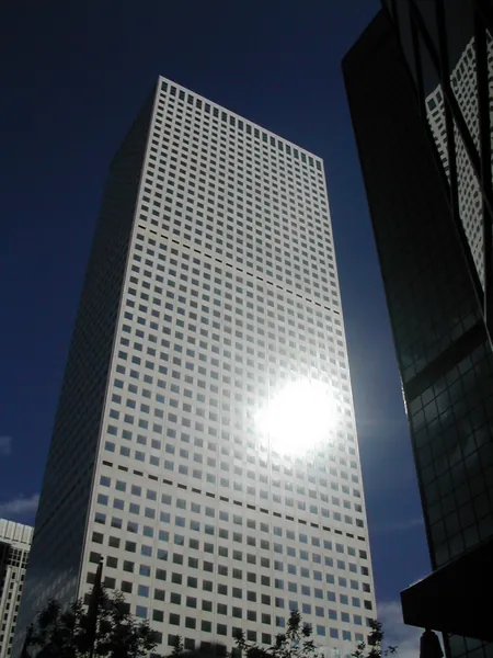 Sunlight glints from a tall modern building.