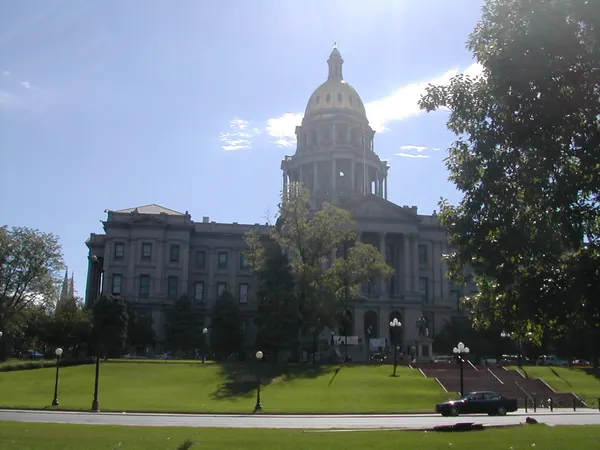 A domed capitol building beyond a green lawn.