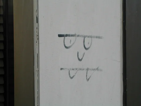A simple smiling face drawn on a pale wall.