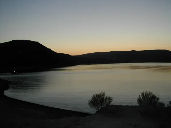 Calm water and dark hills after sunset.